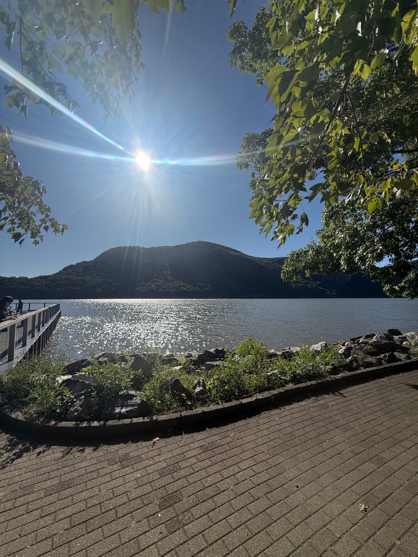 The Cold Spring waterfront, sun over the mountain and a dock reaching into the river