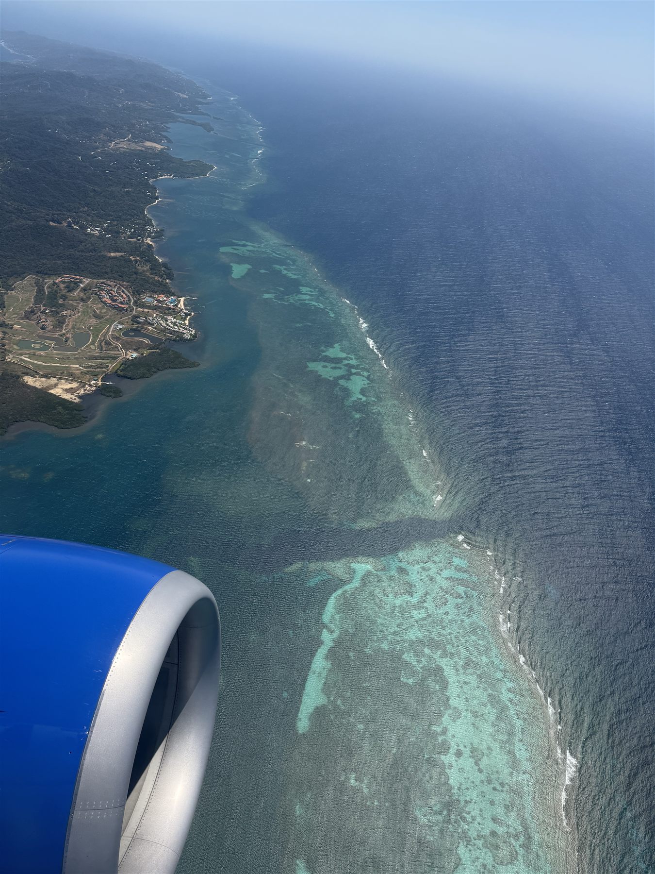 Aerial view of Roatan's barrier reef, the turquoise reef line dropping into deep blue ocean along the island coast
